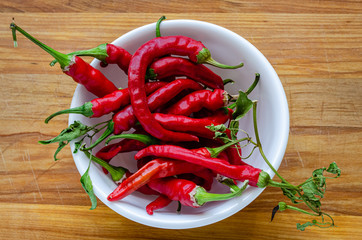 Bowl full of red chili peppers on a wooden cutting board