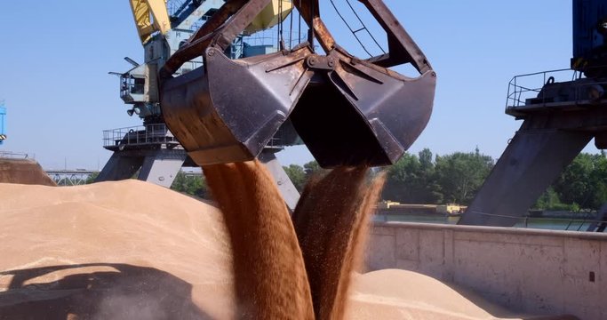 Grapple crane loading ship with wheat in port. Commerce, nautical. Delivery of agriculture cargo by water and freight car. Crane unloading and loading in Harbor