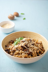 Pearl barley risotto or orzotto with mushrooms and parmesan cheese in bowl on blue concrete background. Selective focus.