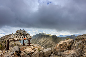 Beautiful, sunlit view from Musala summit on Rila mountain, colorful foreground pile of rocks and dramatic sky