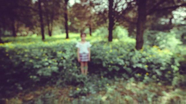 A Girl, Aged 9, Stands In The Midst Of Dense Greenery And Yellow Flowers. The Video Was Shot Using The Stop Motion Technique. The Operator Approaches And Departs From The Girl, The Girl Smiles.