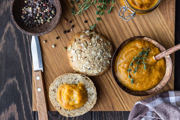 Delicious vegetable caviar in a wooden bowl and jar served with multigrain bread. Homemade caviar with eggplant, tomatoes, carrots and onion. 