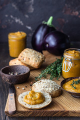 Delicious vegetable caviar in a wooden bowl and jar served with multigrain bread. Homemade caviar with eggplant, tomatoes, carrots and onion. 