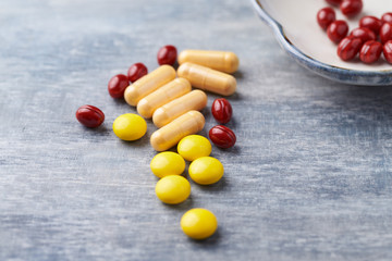 Coenzyme Q10 capsules, Vitamin C and Beta-Carotene tablets. Antioxidants. Concept for a healthy dietary supplementation. Bright wooden background. Close up. Copy space.  
