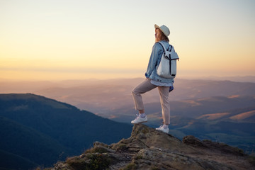 Hiker with backpack in the top of the mountain. Young girl walking in the mountains during sunset....
