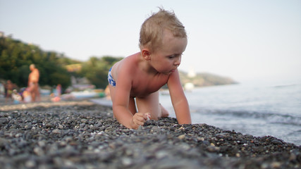 Fototapeta na wymiar Cute child crawling in the shadow on the beach.