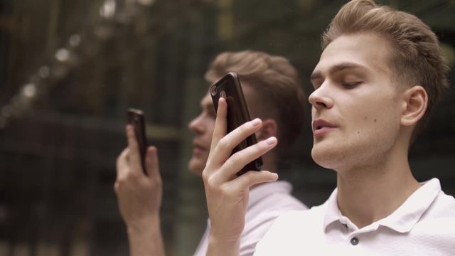 Portrait of positive young handsome guy talking on smartphone with girlfriend