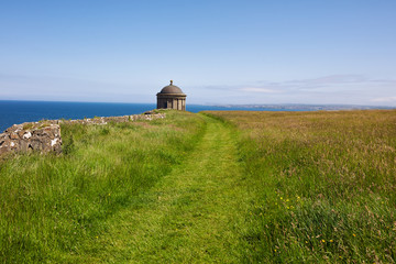 Fototapeta na wymiar Mussenden Temple against blue sky and Atlantic ocean on the North-Western coastline of Northern Ireland