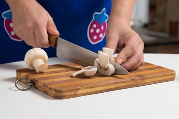 woman cutting champignons mushrooms in kitchen.