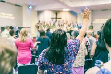 Woman with hands up, worshiping God, at church