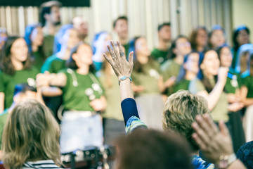People at church, worshiping God, with hands up.