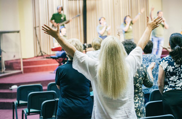Fototapeta na wymiar Woman worshiping God with hands up, at church