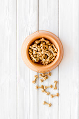 Dog dry food in bowl on white wooden background top view mock-up