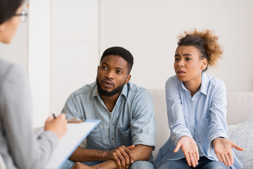 Afro Couple Discussing Family Issues With Counselor Sitting On Couch