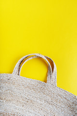 Eco friendly wicker Straw bag over yellow background with space for text, top view, wide composition. Summer vacation fashion, holiday concept. Beach accessories.