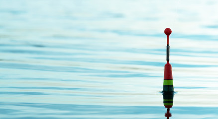 Fishing float in a blue water close up background. © Dmitriy