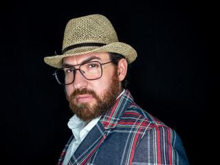 Handsome bearded man in glasses and looking at camera on black background