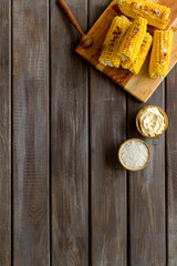 Grilled corn with salt and butter on wooden background top view copyspace