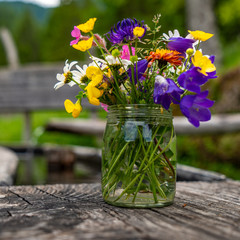 Blumen und Wildkräuter in einem Glas an einem Brunnen