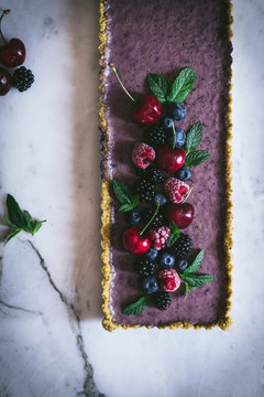 From above ripe tasty cherry blackberry blueberry raspberry with green stems on top of appetizing rectangular cake on white table