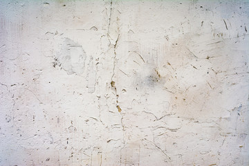 texture of an old wall with uneven cracked stucco, white surface of the exterior painted wall, abstract background