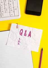 Text sign showing Q And A. Business photo text a period of time or an occasion when someone answers questions Crumpled white paper on table with paper clips clock mobile and pc keyboard