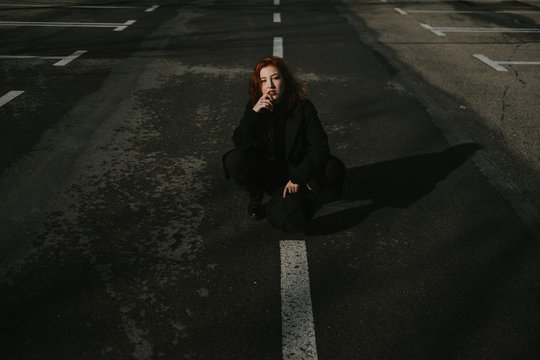 Smiling woman sitting on road with markings