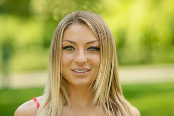 Young smiling woman outdoors portrait. Soft sunny colors. Summer portrait of a beautiful young blonde outdoors in the city.