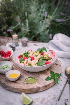 From above appetizing salad and sauce berry sliced lime on wooden stand with salt and pepper on table
