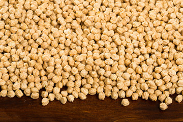 Closeup of background with raw garbanzo grains  on wooden  surface