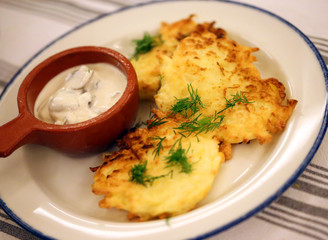 Delicious pancakes with potatoes and sour cream on a saucer