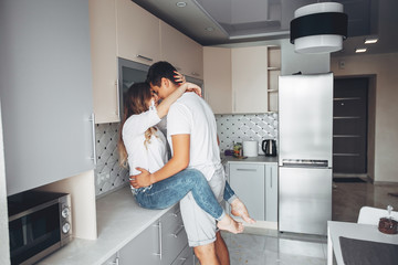 Loving couple have fun at home. Pretty blonde in a white blouse. Man and woman standing in a kitchen