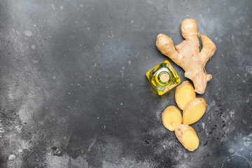 Healing Ginger oil and fresh ginger root, gray kitchen table, copy space, top view