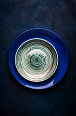 Empty blue ceramic plate on blue background, ready to serve, top view vertical