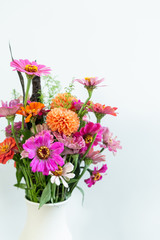 Fototapeta premium pink daisy flowers and orange ball dahlia flower, colorful summer bouquet in vase, white background