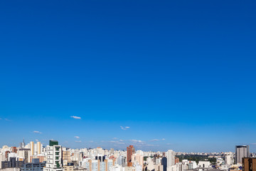 Aerial view of streets and avenues in Pinheiros neighborhood with commercial buildings and small houses at dusk on sunny summer day. The neighborhood has old houses and modern office buildings.