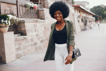 Fashionable girl in a summer city. Black lady in a green jacket
