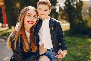 Family in a summer park. Mother in a black jacket. Cute little boy