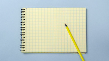 Top view of open blank notebook with pencil on blue desk background.