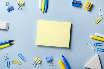 Sticky note paper on the desktop with yellow and blue pencils and felt-tip pens.