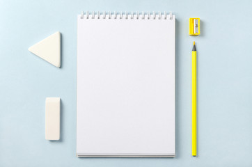 White notebook, pencil sharpener, pencil and eraser. Top view with copy space.
