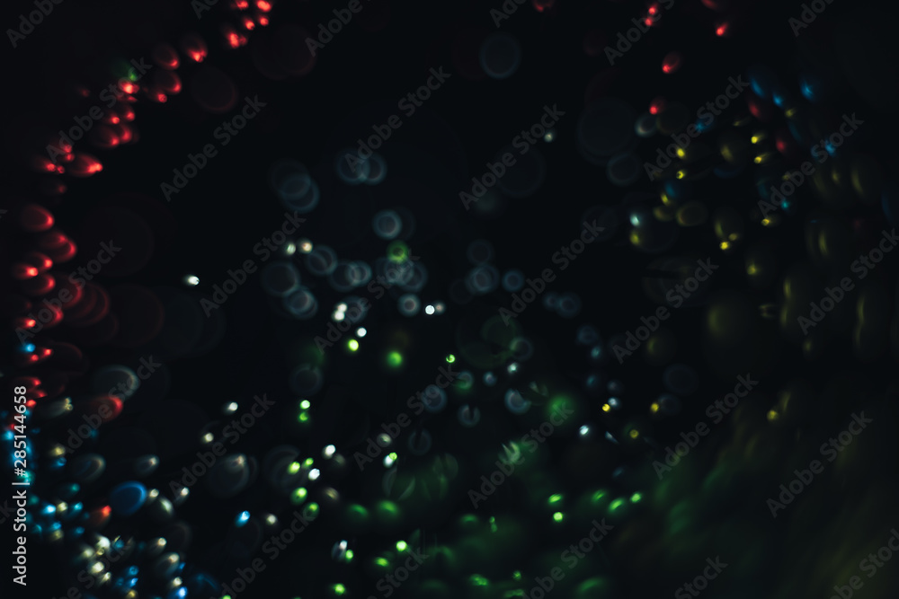 Poster beautiful multi colored light bokeh on a black background.