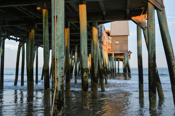 Underneath a seaside Maine pier bathed in golden sunset light