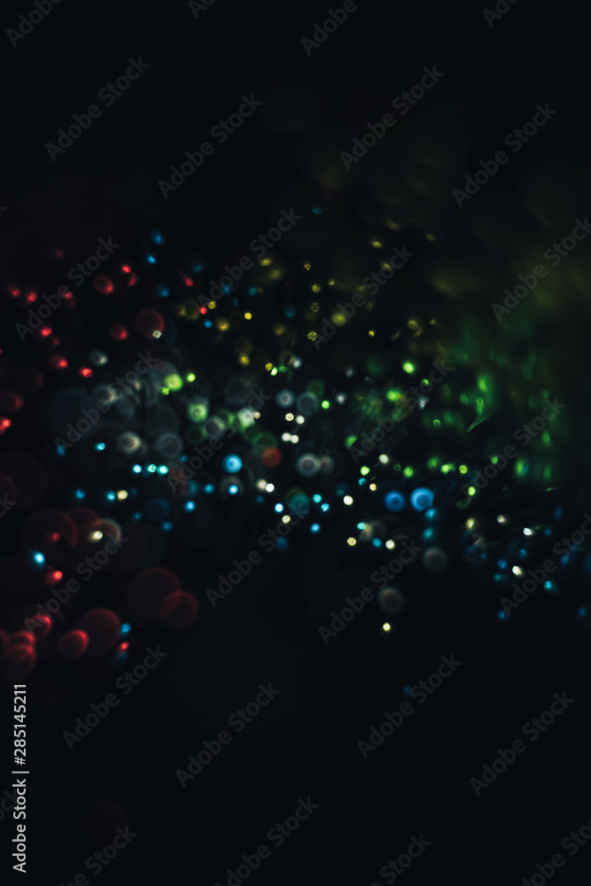 Poster beautiful multi colored light bokeh on a black background.