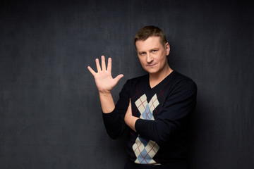 Portrait of satisfied man raising hand with spread fingers