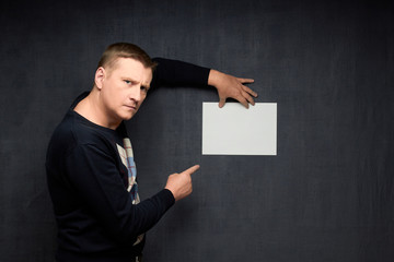 Portrait of serious man holding paper sheet and pointing at it