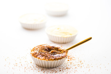 Caramelising sugar on top of creme brulee with flaming torch on a white background