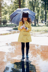 Little girl in a rain coat. Child playing in a park.