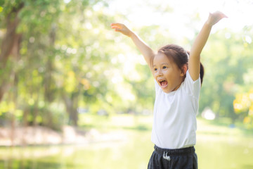 Beautiful young asian child smiling and cheerful playing at park, asia kid confident jump and fun in the garden activities outdoor at garden in nature summer, lifestyle concept.