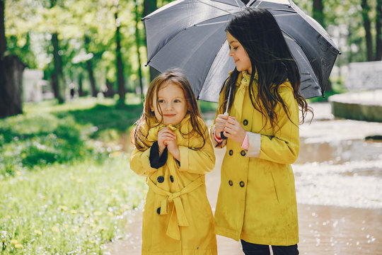 Kids in a rain coats. Children in a park. Two cute sisters